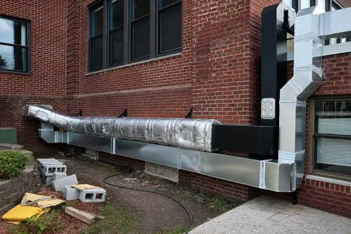 Completed exterior insulated ductwork along a brick building