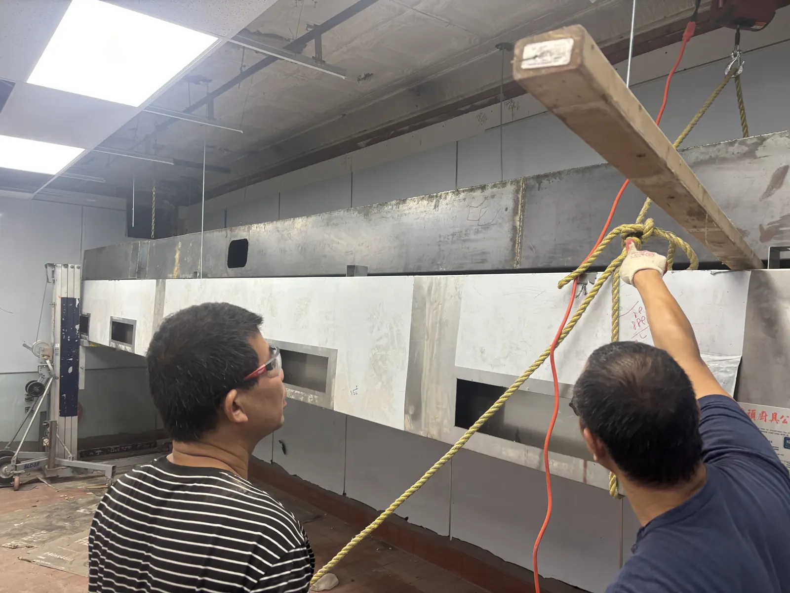 Two crew members guiding a hood section into place