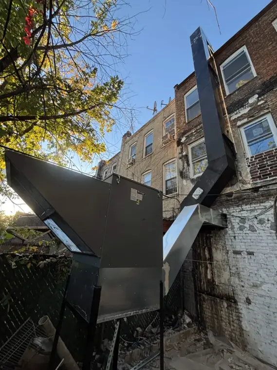 New make-up air unit on a steel stand beside a three-story exhaust riser