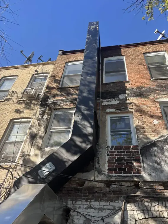 Exhaust riser running up the rear wall of a three-story building
